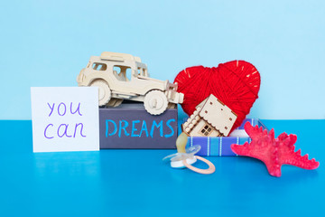 Word Dreams written on gift box, heart, car, house, starfish and pacifier on the blue background.