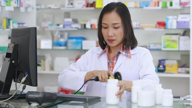 Pharmacist scanning barcode on white bottle medicine to add information on computers in drugstore 4K video footage