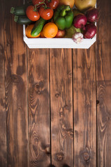 Box with vegetables and fruits on a wood background from boards. Shopping, nutrition and lifestyle