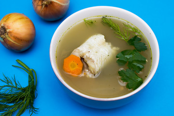 Traditional fish soup. Blue background. Fish soup is a food made by combining fish or seafood with...