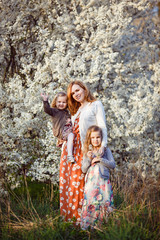 mom with daughters by bush with white flowers