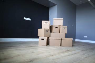 Close-up of unpacked cardboard boxes. Empty room with personal stuff packed in carton. Purchased apartment or house property. Moving day and renovation concept