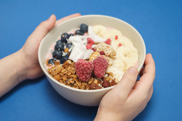 Child holds in hand Handmade Bowl with healthy tasty breakfast