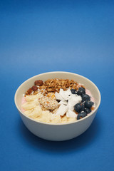 Handmade Bowl healthy tasty breakfast of yogurt, smoothie with granola, nuts, bananas and berries