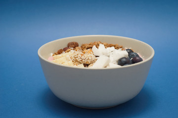 Handmade Bowl healthy tasty breakfast of yogurt, smoothie with granola, nuts, bananas and berries