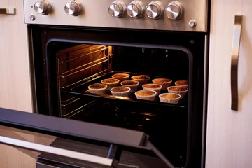 Foto op Plexiglas Baked cupcakes in an open oven close-up. © Viktoriia