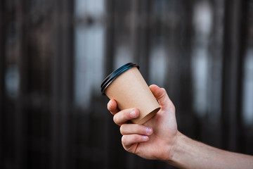Cup of coffee in human hands. Cup of coffee. Coffee. Cardboard cup. Gray background.