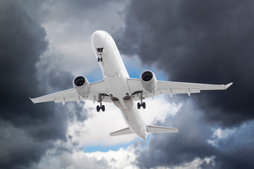 white plane take off in stormy grey and white clouds on blue sky background