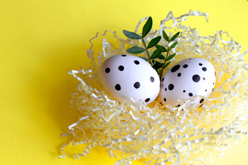 Colorful easter eggs in paper nest decorated with flower and leaves on yellow pastel background. Haapy easter! easter greeting card