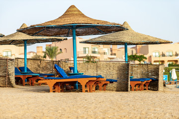 Group of straw umbrellas and deck chairs in a Red Sea sandy beach, tourist resort near Marsa Alam, Egypt, Africa 