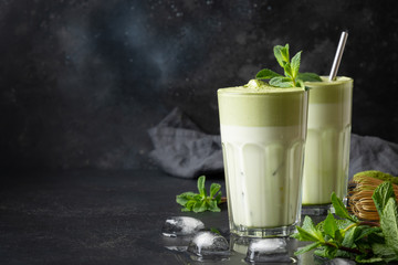 Two glasses of Dalgona iced latte matcha tea and ingredients on black background. Copy space. Close...