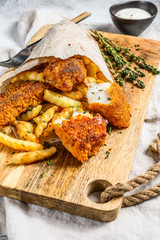 Fish and chips, French fries and cod fillet fried in breadcrumbs. Gray background. Top view