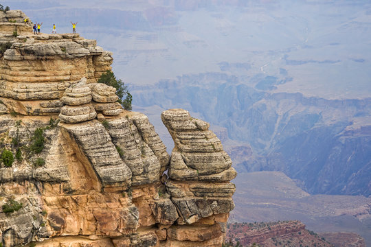 Fröhliche Menschen recken die Arme hoch am Rand des Grand Canyon