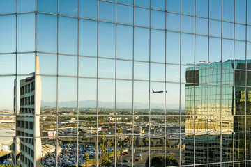 Fototapeta na wymiar Landendes Flugzeug spiegelt sich in der Glasfassade eines hohen Gebäudes