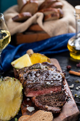 Finely cooked and sliced meat steak served with pineapple on a wooden board