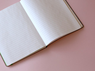 white copybook with pen on punchy pastel pink. Working desk. Copy space. Top view. Flat lay. Female accessories for target planning.