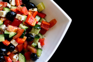 fresh greek salad in white plate on black table. vegetable salad with feta cheese. healthy food.