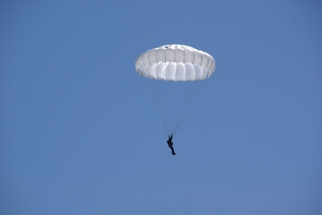 Close-up of a skydiver on a white parachute in a blue sky