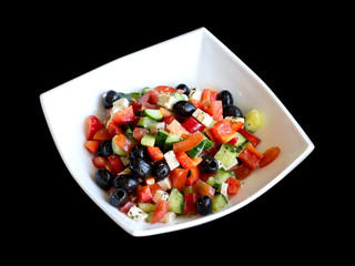 fresh greek salad in white plate on black table. vegetable salad with feta cheese. healthy food.
