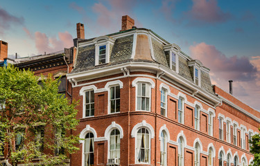 Old red brick building with arched windows and a mansard roof