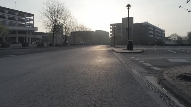 Drone flying aerial view across retail empty car park during COVID corona virus lock down at sunrise