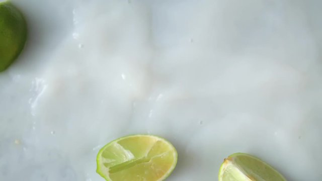 Sliced fresh lemon falling into milky water. Organic Fruit is dropped into white liquid with splashes. Filmed in Prores.
