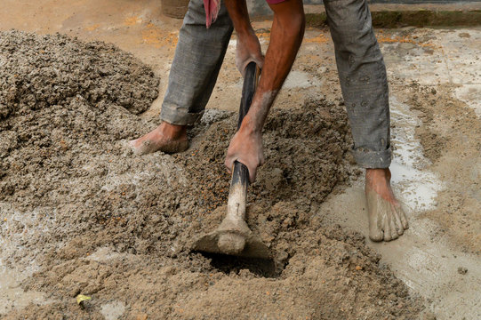 Indian labour mixing cement using shovel.