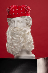 White plaster statue of a bust of Apollo Belvedere with a long white beard and a red bandana scarf