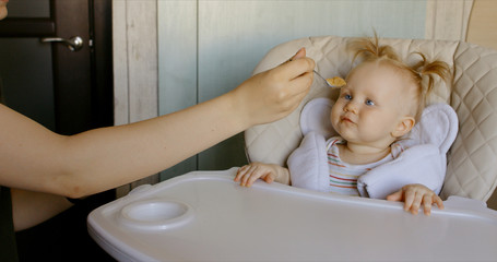 Caucasian mother feeding baby with spoon