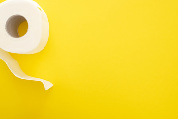 Fototapeta na wymiar top view of white toilet paper roll on yellow background