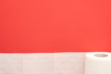 top view of white toilet paper roll on red background with copy space
