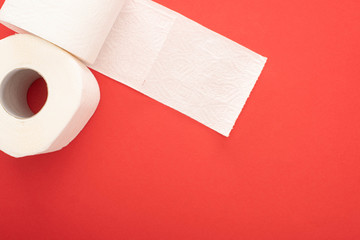 top view of white toilet paper rolls on red background with copy space