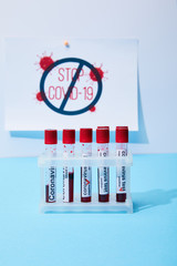 selective focus of test tubes with coronavirus test samples near paper with stop covid-19 lettering...