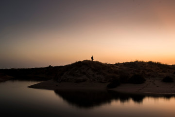 Men standing on hill in the water at sunset
