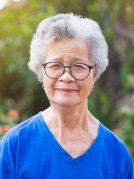 Portrait of elderly woman with short white hair standing smile and looking at the camera in garden. Asian old woman healthy and have positive thoughts on life make her happy every day. Health concept