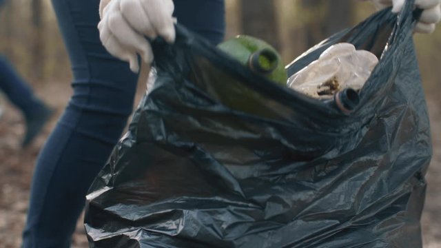 Woman putting household waste into bin bag
