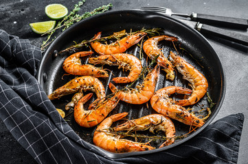 Grilled giant langoustine shrimps, prawns in a frying pan. Black background. Top view