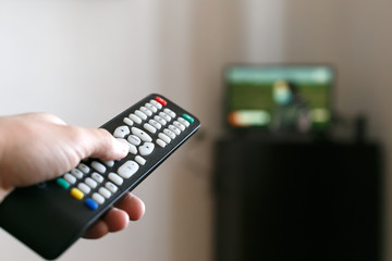 Hand of a man with a remote control from the TV.