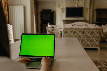 Woman using laptop with green screen. Woman's hands typing on a laptop keyboard. Business, communication, freelance and internet concept