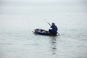 the man rowing a old small wooden rowboat