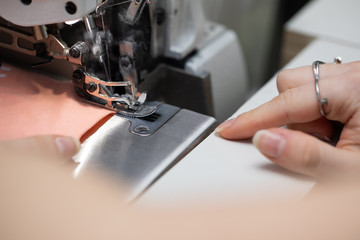 A young schoolgirl learns to sew face masks during a pandemic on an overlock sewing machine.