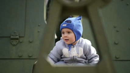 Portrait of little boy near military equipment in museum the park