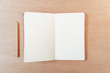 Blank open notebook with a pencil in a wooden background, flat lay, copy space, template