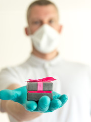 Homme avec masque et gants offrant un cadeau