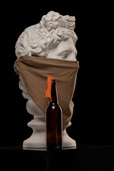 White plaster statue of a bust of Apollo Belvedere in a headscarf covering his face and with a...
