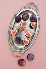 Fresh figs on vintage silver tray on pink background