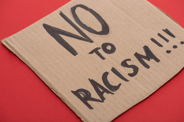 carton placard with say no to racism lettering on red background