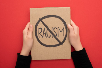 cropped view of woman holding carton placard with stop racism sign on red background