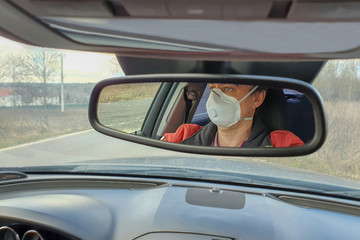 A man drives a car in a protective mask during an epidemic
