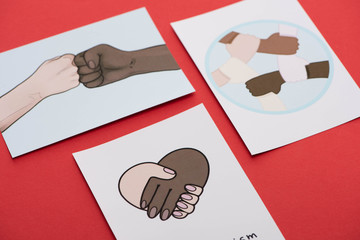 close up view of pictures with multiethnic hands on red background